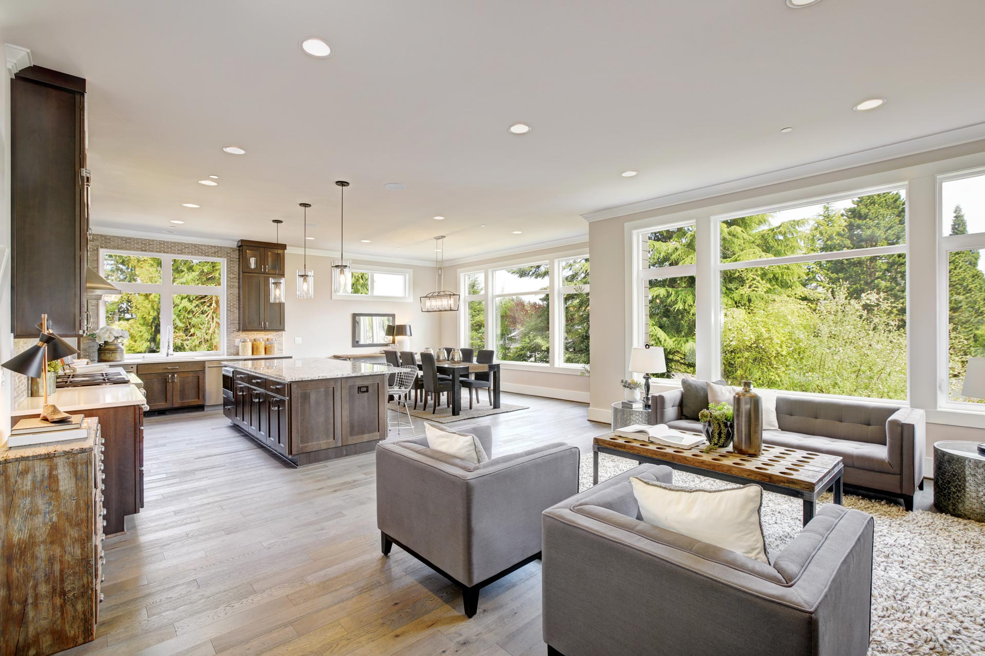 An open concept living room and kitchen with large windows.